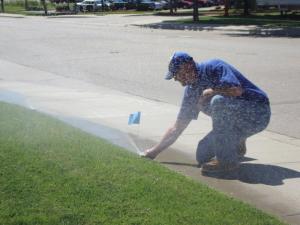 a Hallandale beach sprinkler repair tech is adjusting a sprinkler head